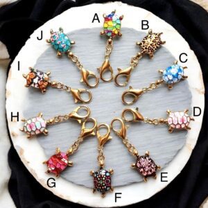 Twelve colorful charm pendants arranged in a circle on black fabric.