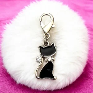 Black cat keychain on fluffy white background.