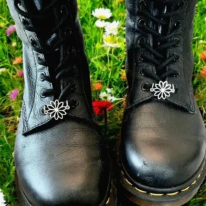 Black boots with floral charms on grass.
