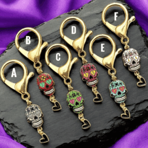Colorful skull keychains with alphabet tags on a black slate.