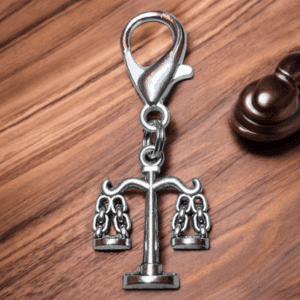 A keychain shaped like a balance scale with male and female symbols.