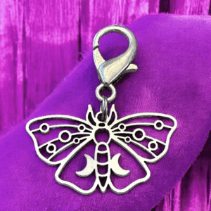 Silver butterfly charm with intricate cut-out design on purple fabric.