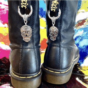 Black boots with skull keychain accessories on a colorful background.