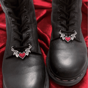 Black boots with heart-shaped charms on red fabric.