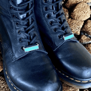 Close-up of worn black leather boots on rocky ground.