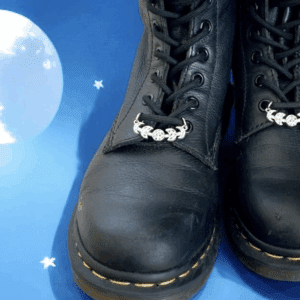 Black combat boots with decorative floral charms on a starry blue background.