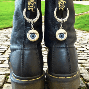 Black boots with unique eyeball keychain accessories attached to the back.