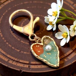 Heart-shaped keychain with beads and small flowers on wood.