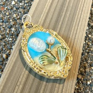 Vintage gold pendant with a blue background and floral design.