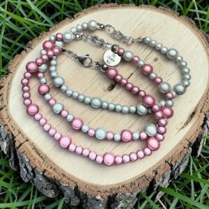 Three beaded bracelets in shades of pink and gray on wood.