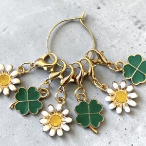 Gold hoop earrings with green four-leaf clover and white daisy charms.