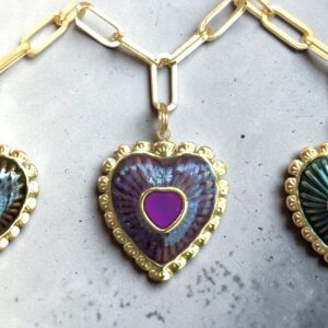 Three heart-shaped lockets with intricate gold detailing on a marble surface.